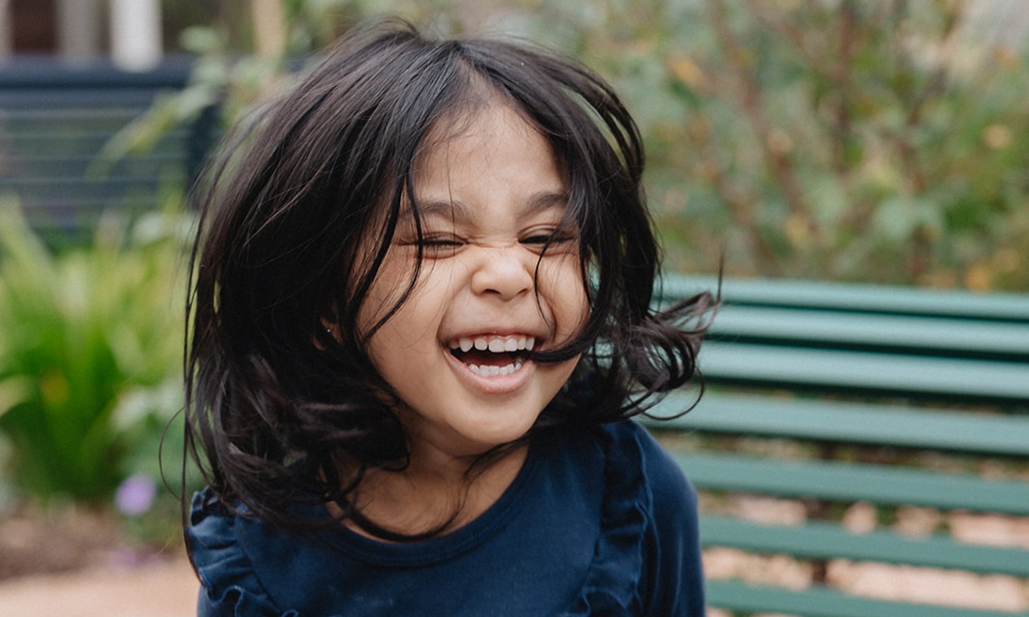A laughing child holding a purple flower