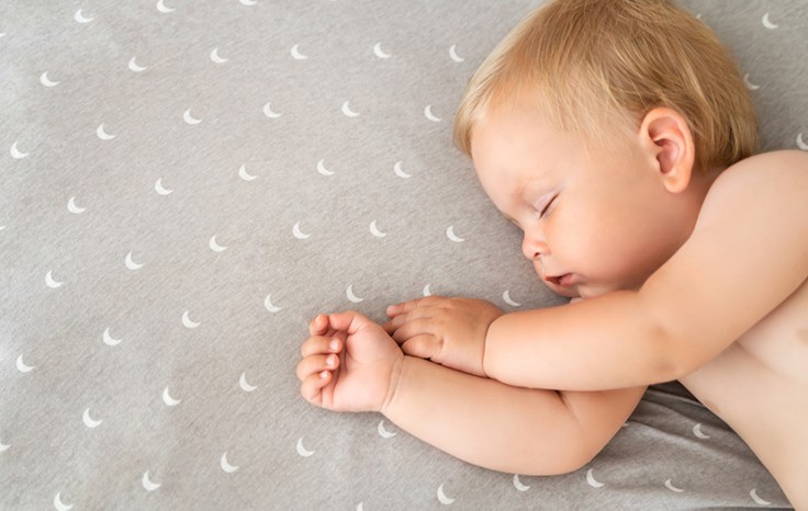 Closeup of baby sleeping in bed watching sweet dreams after active play in bedroom