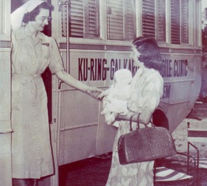 A black and white image of a Karitane nurse smiling at a mum and her baby