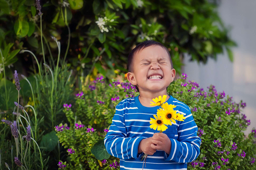 A happy boy holding a bunch of flowers