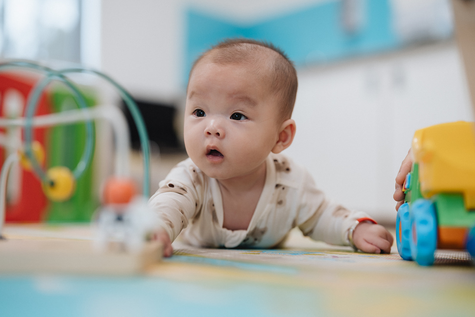A baby having tummy time on the floor with toys