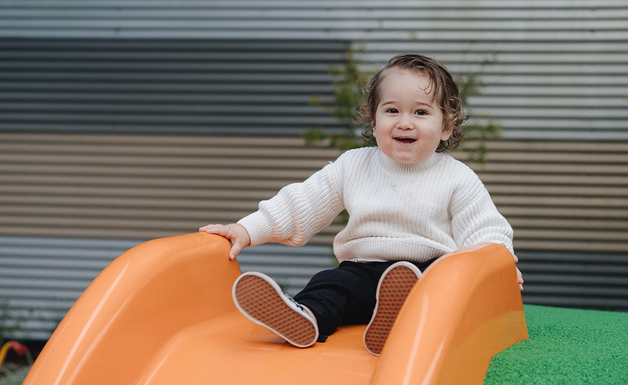 Karitane Baby smiling at the top of a slide