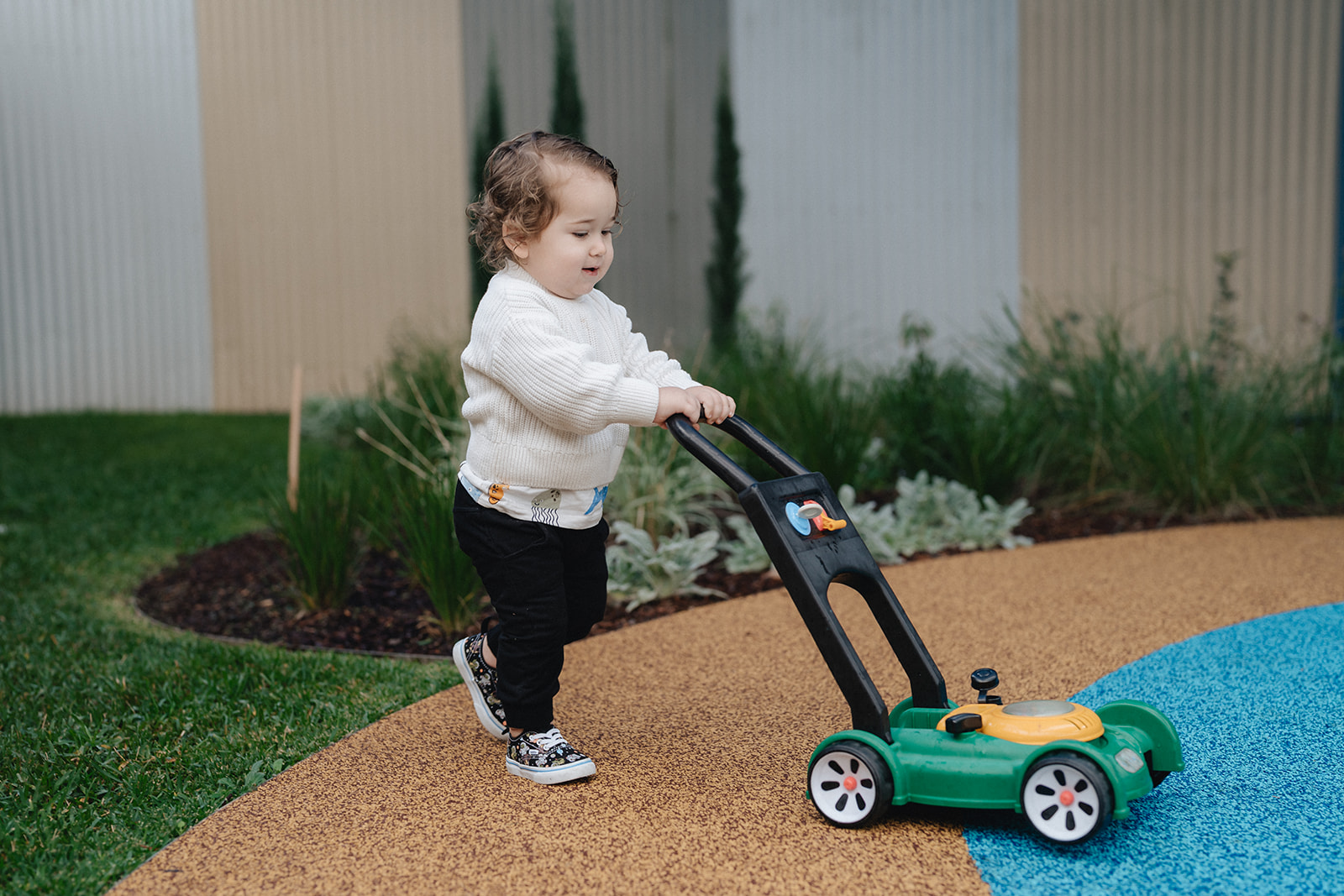 A small toddler pushing a child toy mower